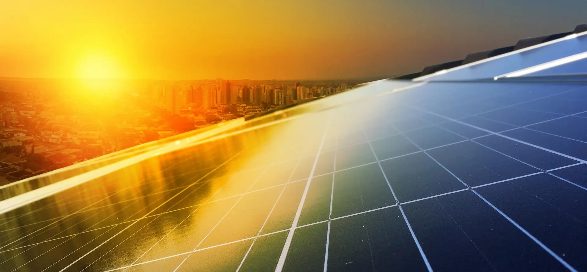 Commercial rooftop solar panels at sunset with city skyline in background